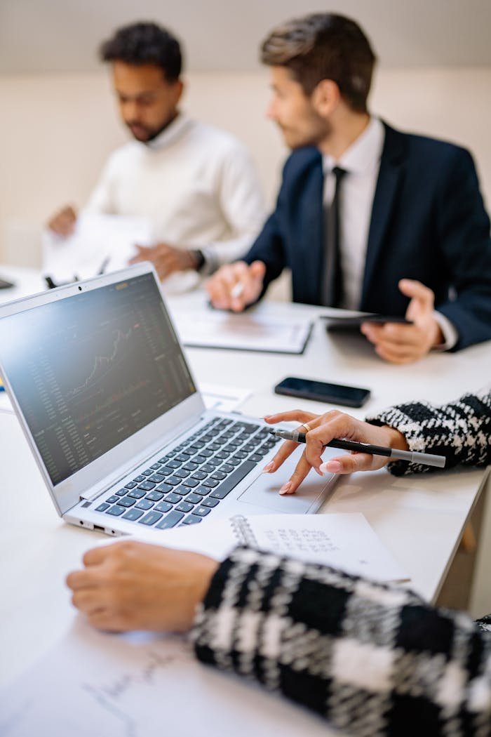 Professionals collaborating with technology to analyze stock market trends on a laptop.